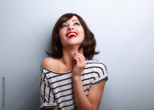 Happy natural toothy laughing young woman looking up
