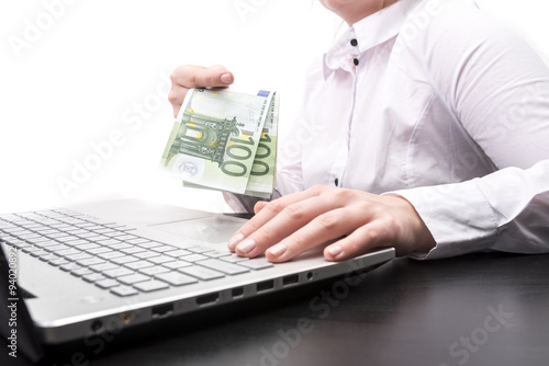 Kobieta trzymająca pieniądze Euro przed laptopem