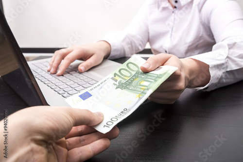 Przekazywanie pieniędzy Euro kobiecie przy laptopie