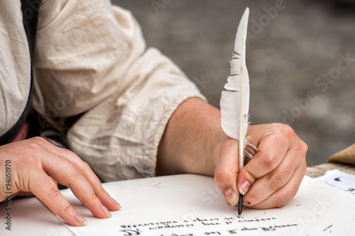 hands writing a letter with a plume
