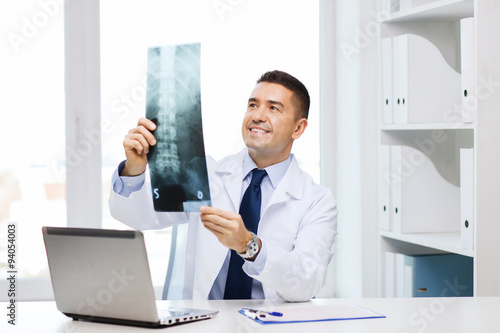 smiling male doctor in white coat looking at x-ray