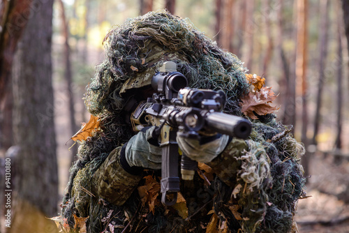 Sniper aiming from his rifle in forest/Portrait of sniper in the woods, which aiming from his rifle