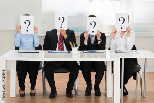 Businesspeople Hiding Face With Question Mark Sign