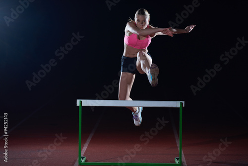 woman athlete jumping over a hurdles