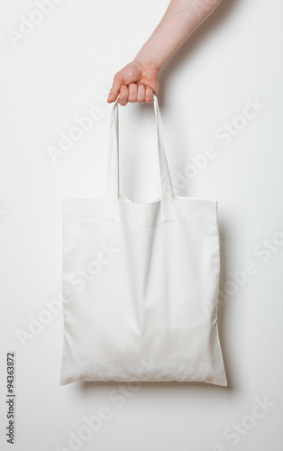 Male hand holding white textile bag