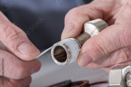 Plumber putting a teflon joint on a thread