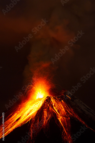 A powerful eruption from the volcano sends dark clouds of magma into the sky, glowing with intense heat and energy.