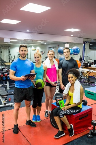 Fit people smiling at camera in weights room