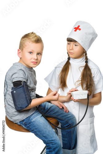 Cute doctor girl measuring blood pressure of a boy patient isolated on white background