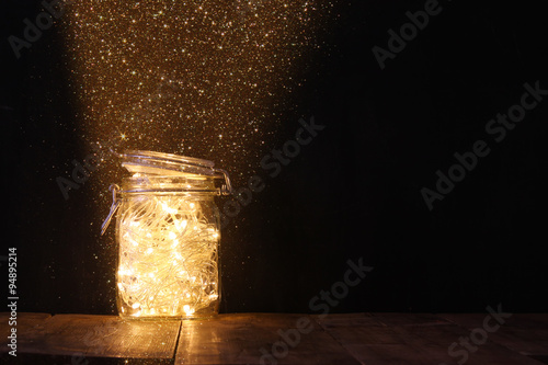 low key and vintage filtered image of fairy lights in mason jar with. selective focus. 