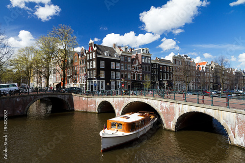 Amsterdam canal intersection with white boat in summer with a blue sky