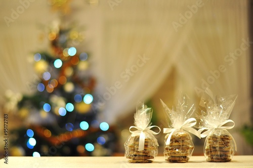 Domowe, świąteczne pierniki w ozdobnych paczuszkach na tle choinki