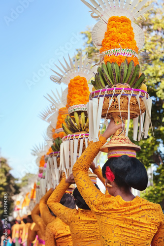 Procession of beautiful Balinese women in traditional costumes - sarong, carry offering on heads for Hindu ceremony. Arts festival, culture of Bali island and Indonesia people, Asian travel background