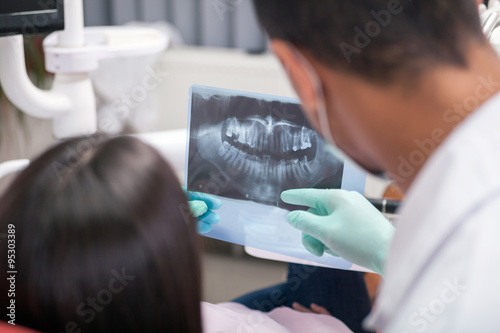 closeup of dentist explaining the details of x-ray picture to hi