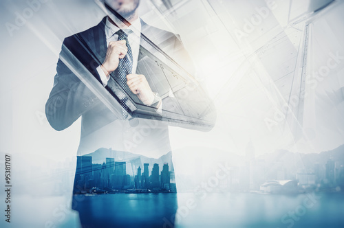 Close-up portrait of businessman straightens his own tie. Double exposure city at sunrise. Horizontal