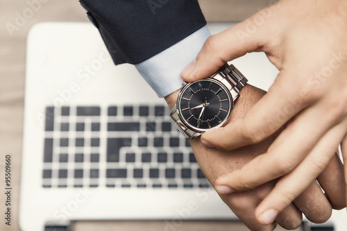 mano di uomo in ufficio con orologio al poloso e tastiera di notebook