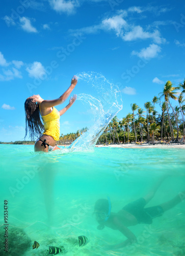 Beautiful young woman in bikini on the sunny tropical beach rela