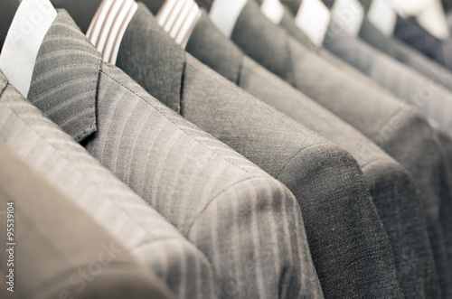 Men suits hanging in a clothing store.