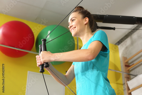 Siłownia, trening z gumami. Kobieta trenuje w sali gimnastycznej