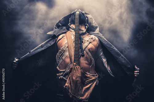 man in the gas mask in the hood, on the black background surrounded by smoke, , survival soldier after apocalypse.