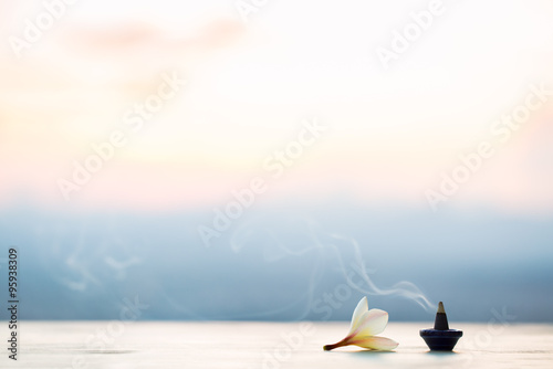 Smoke incense cones with plumeria flower on sunset
