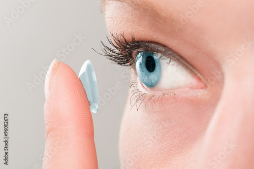 Woman inserting a contact lens in eye.