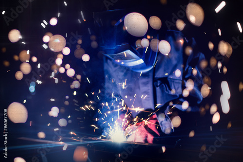 Employee welding steel with sparks using mig mag welder - focus on sparks.