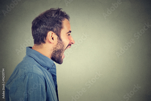 Side profile portrait of young angry man screaming