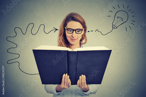 Woman in glasses reading big book comes up with an idea