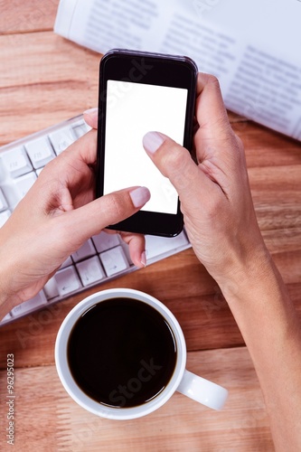 Businesswoman using her smartphone on desk