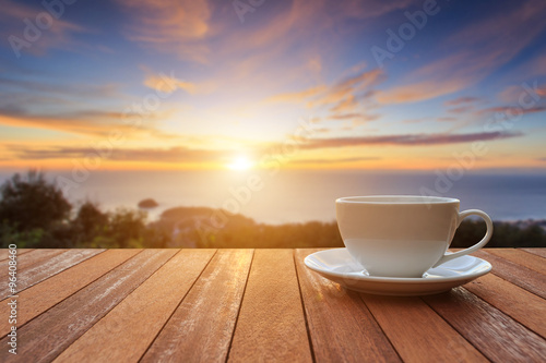 White coffee cup on wood table and view of sunset or sunrise bac