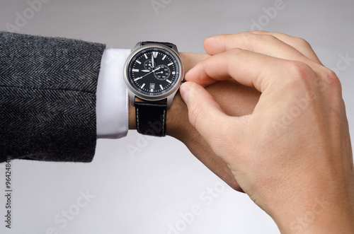 businessman adjusts the time on his wristwatch