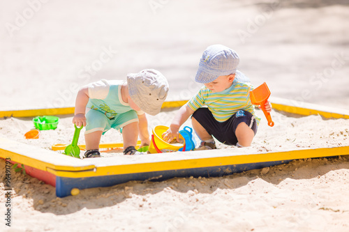 Two baby boys playing with sand