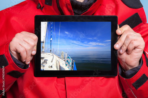 Man sailor showing yacht boat on tablet. Sailing