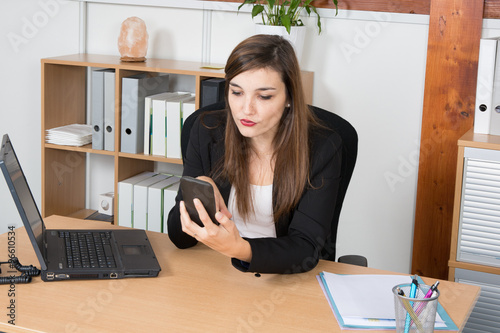 Image of a businessperson dialing a number using the smartphone on the foreground