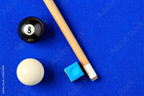 Billiard balls, cue and chalk in a blue pool table.