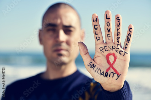 young man with a red ribbon for the fight against AIDS in his ha