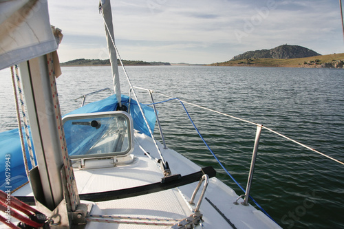 Prow view of sailboat sailing across Alange Reservoir, Spain