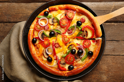 Delicious pizza with vegetables, on wooden table