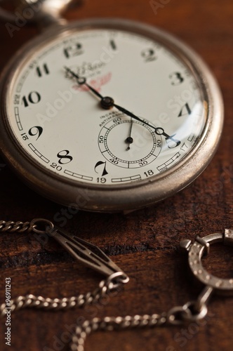 orologio antico da tasca in argento con catenella appoggiato su tavolo di legno