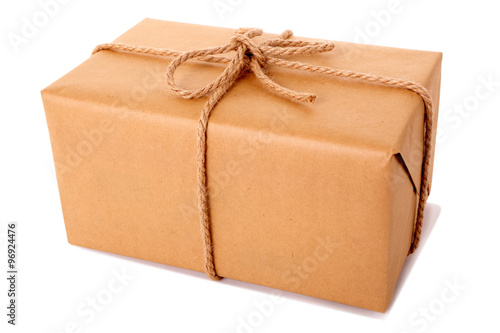 One single small plain brown paper package parcel gift or present tied with string shipping box delivery isolated on white background photo