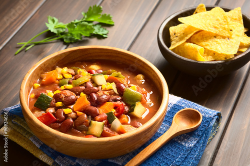 Vegetarian chili dish made of kidney bean, carrot, zucchini, bell pepper, sweet corn, tomato, onion, garlic, photographed with natural light (Selective Focus, Focus in the middle of the dish)