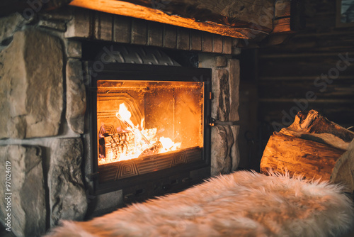 Warm cozy fireplace with real wood burning in it. Cozy winter concept. Christmas and travel background with space for your text