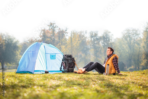 Young male camper sitting on grass