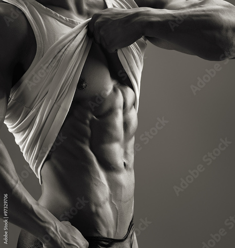 Muscular man lifts the shirt and showing the chest and abdomen. Black and white image. 