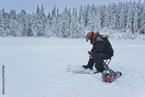 Man is ice-fishing in Ruka in Lapland in winter