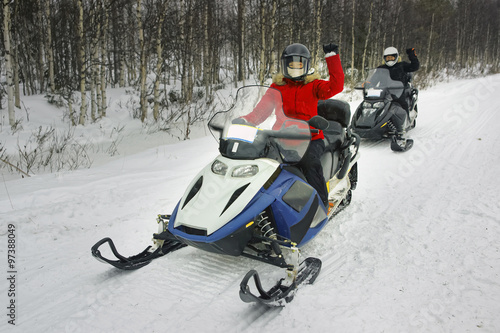 Woman and Man driving snowmobile in Ruka of Lapland