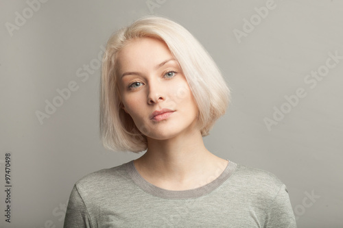 close up portrait of young beautiful blonde woman on gray background