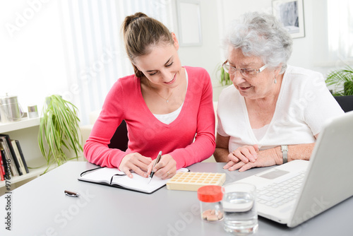 cheerful young woman helping an elderly woman with pills medical prescription