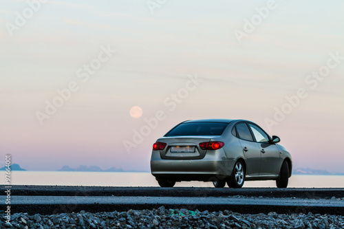 One sedan ar on a road against background with lake and mountains